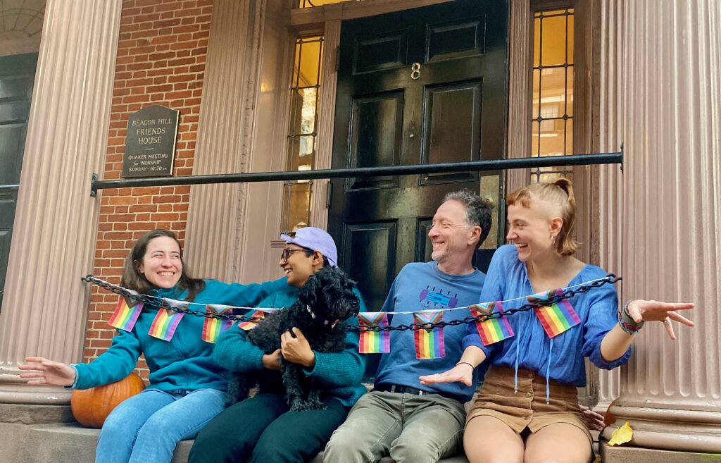 Four Friends House residents (and one dog) sit on the front porch of the Friends House